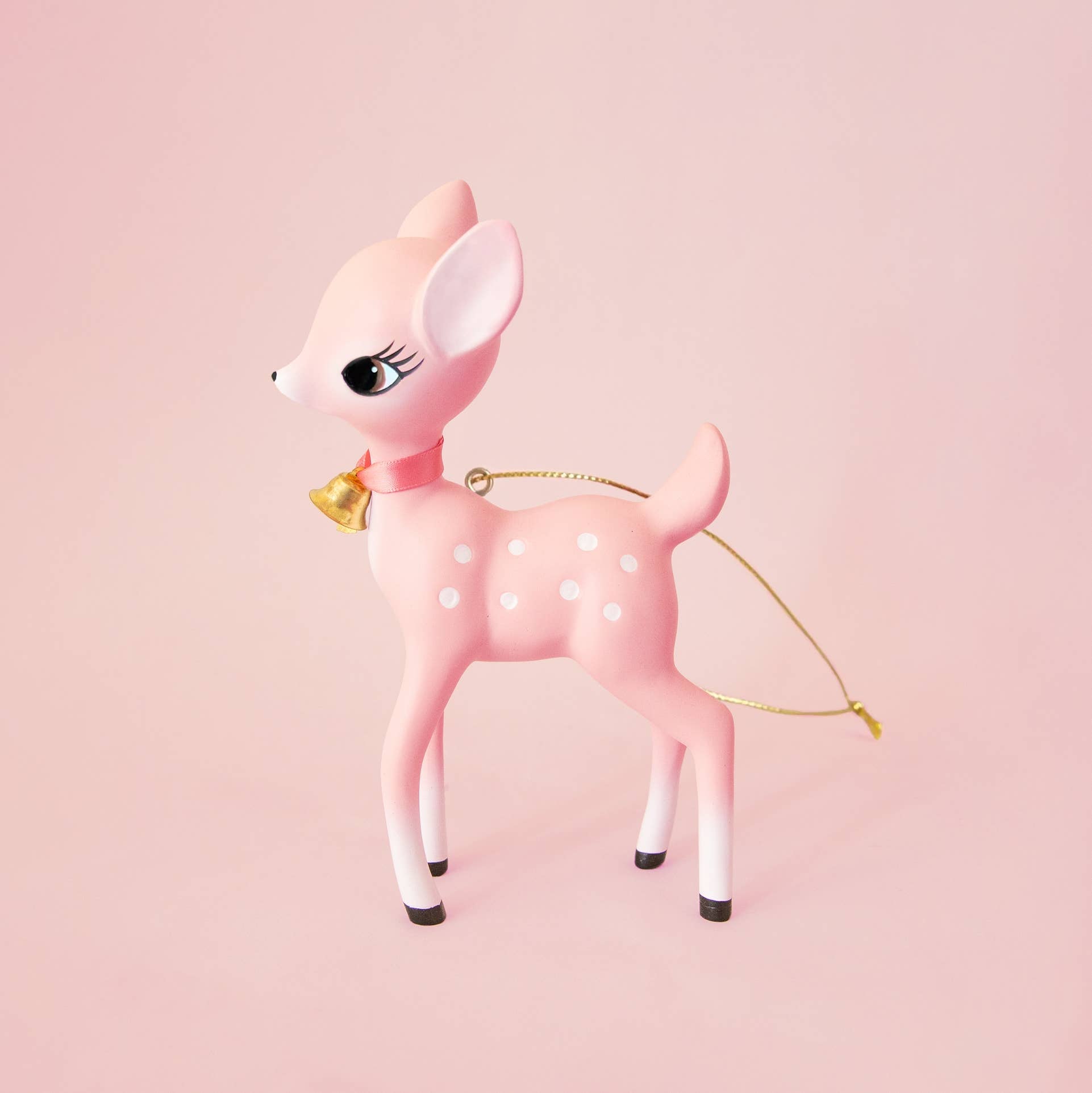 Pink deer figurine with a gold bell on a pink background