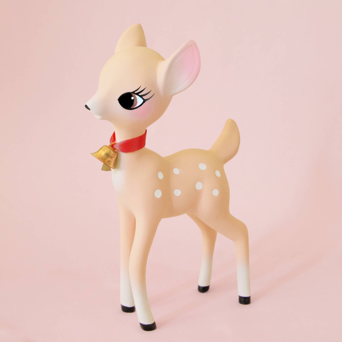 Deer figurine with a red bow on a pink background