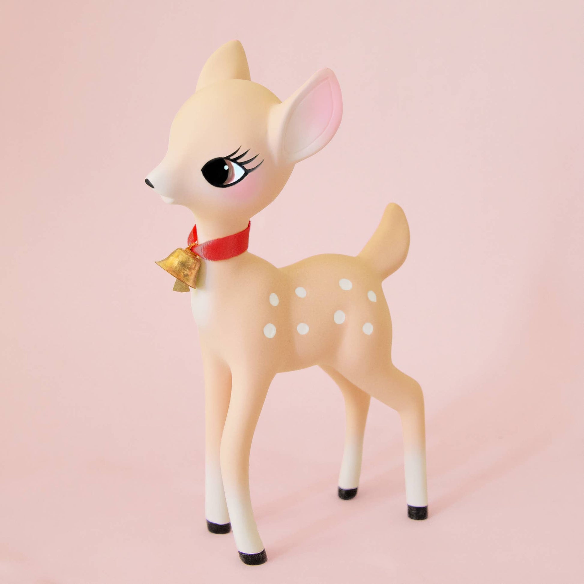 Deer figurine with a red bow on a pink background