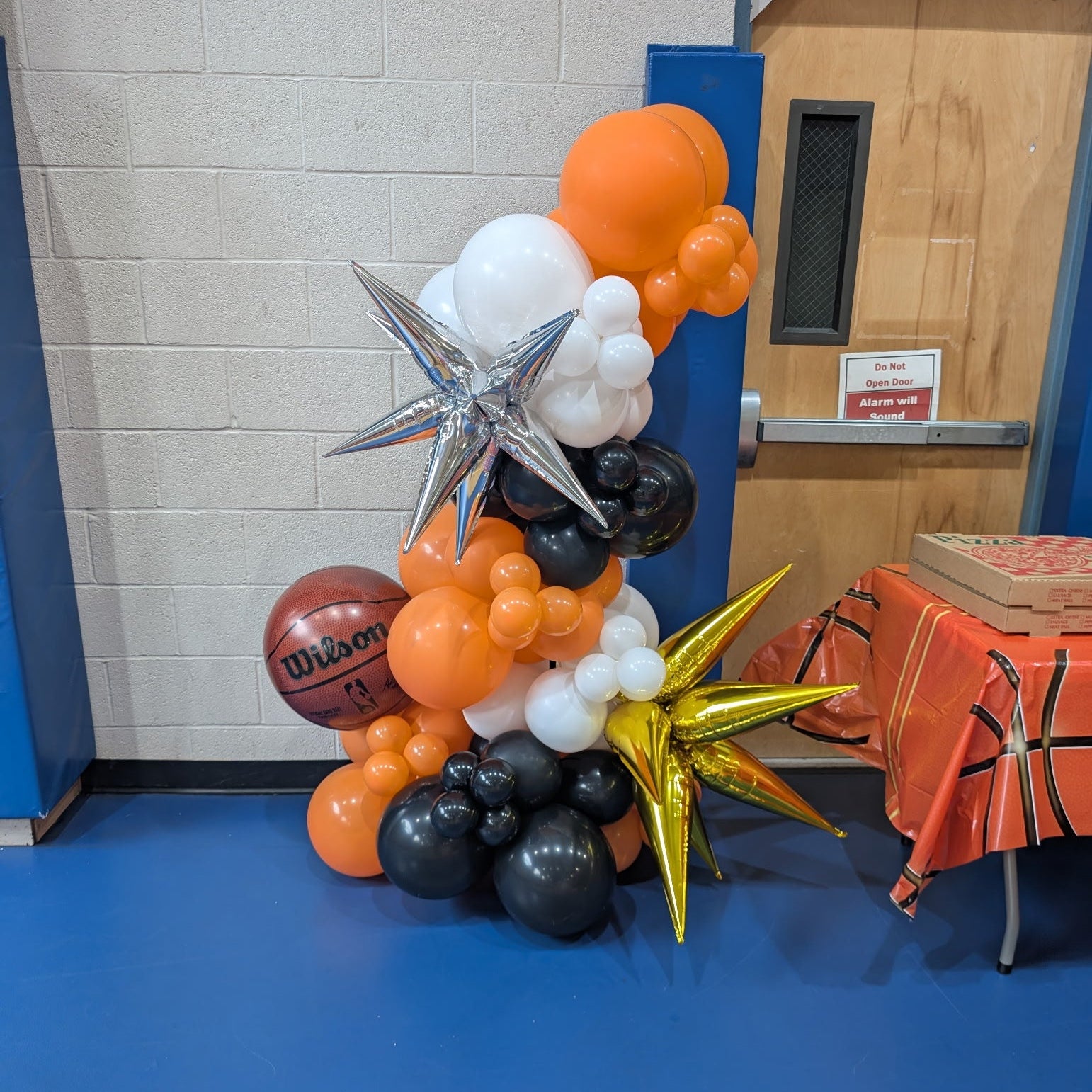 basketball themed custom free standing balloon garland on base in orange white and black with foil balloon accents